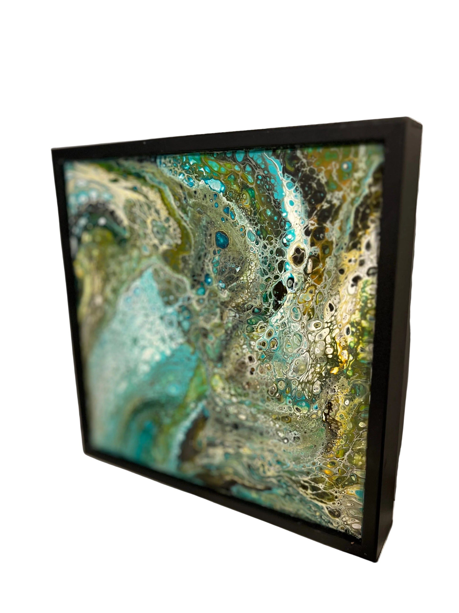 Framed abstract art piece, poured acrylics with a black frame on a white surface.