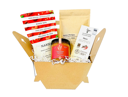 Open box containing various snacks and a jar of honey on a white background