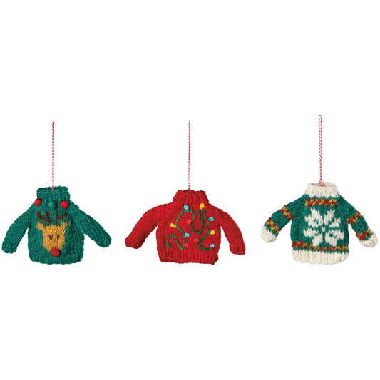 Three knitted Christmas sweater ornaments hanging on a white background, featuring green with a yellow reindeer, red with colorful ornaments, and green and white with a snowflake design.